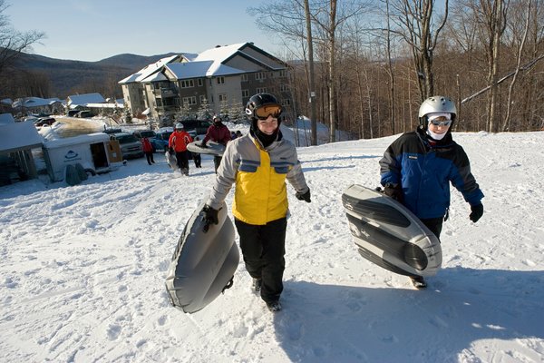 Two Snow Sliding Visitors at Smugglers' Notch Resort in Vermont enjoy winter activities during Winter Carnival.